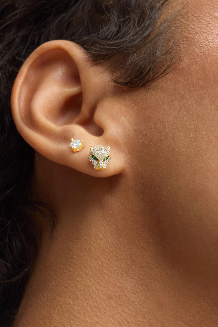 Gold-tone stud earrings on ear, including jaguar pave with green eyes