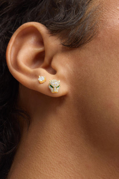 Gold-tone stud earrings on ear, including jaguar pave with green eyes