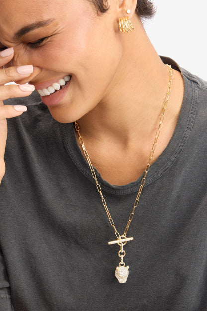 Gold tone chain necklace worn with dangling jaguar head pendant and bar clasp