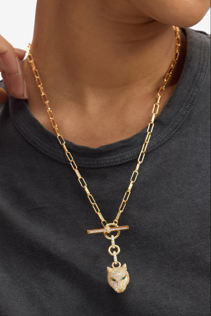 Gold tone chain necklace detail: bar clasp with loop and dangling jaguar head charm