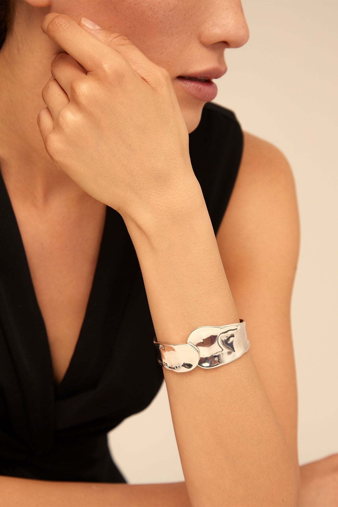 Silver cuff bracelet on wrist, polished finish with sculpted front detail