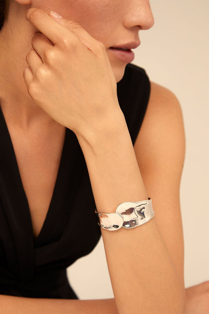 Silver cuff bracelet on wrist, polished finish with sculpted front detail