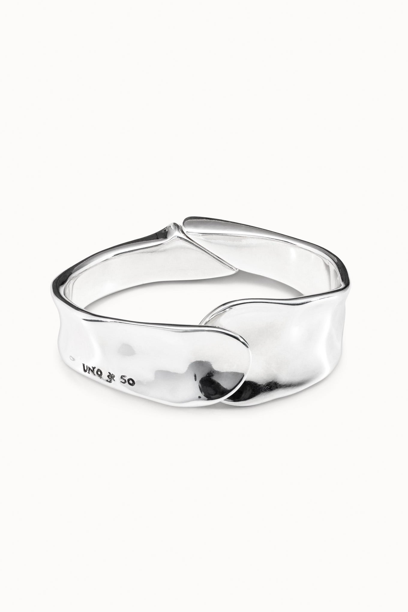 Silver cuff bracelet, polished curved band with raised center emblem