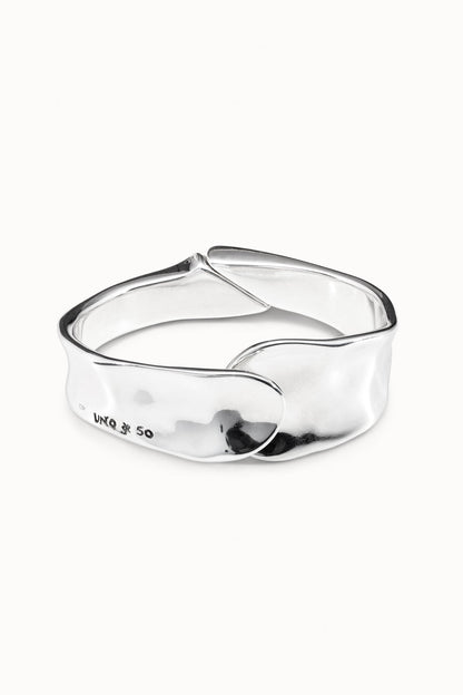 Silver cuff bracelet, polished curved band with raised center emblem