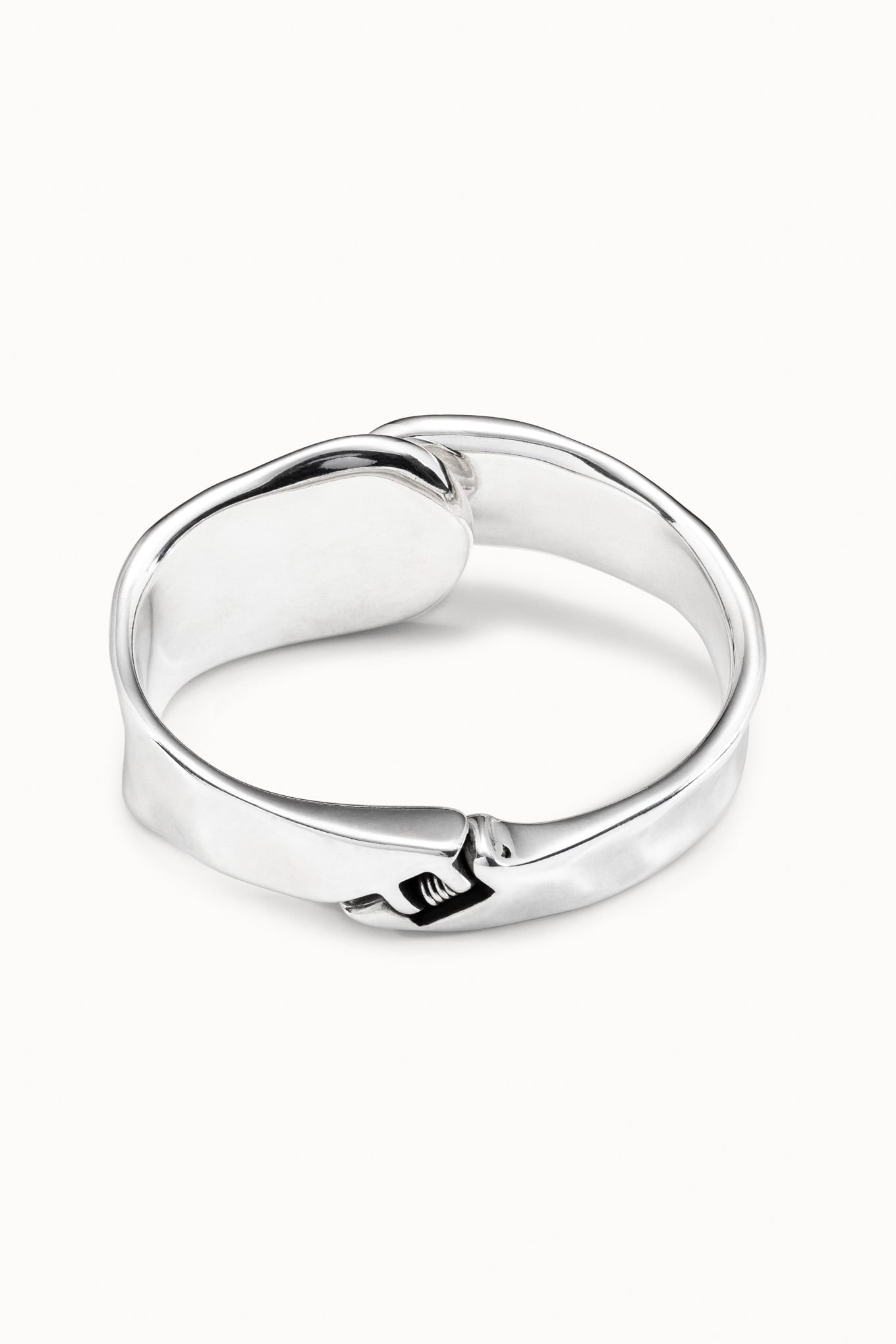 Silver cuff bracelet, wide polished band with curled sculpted emblem front