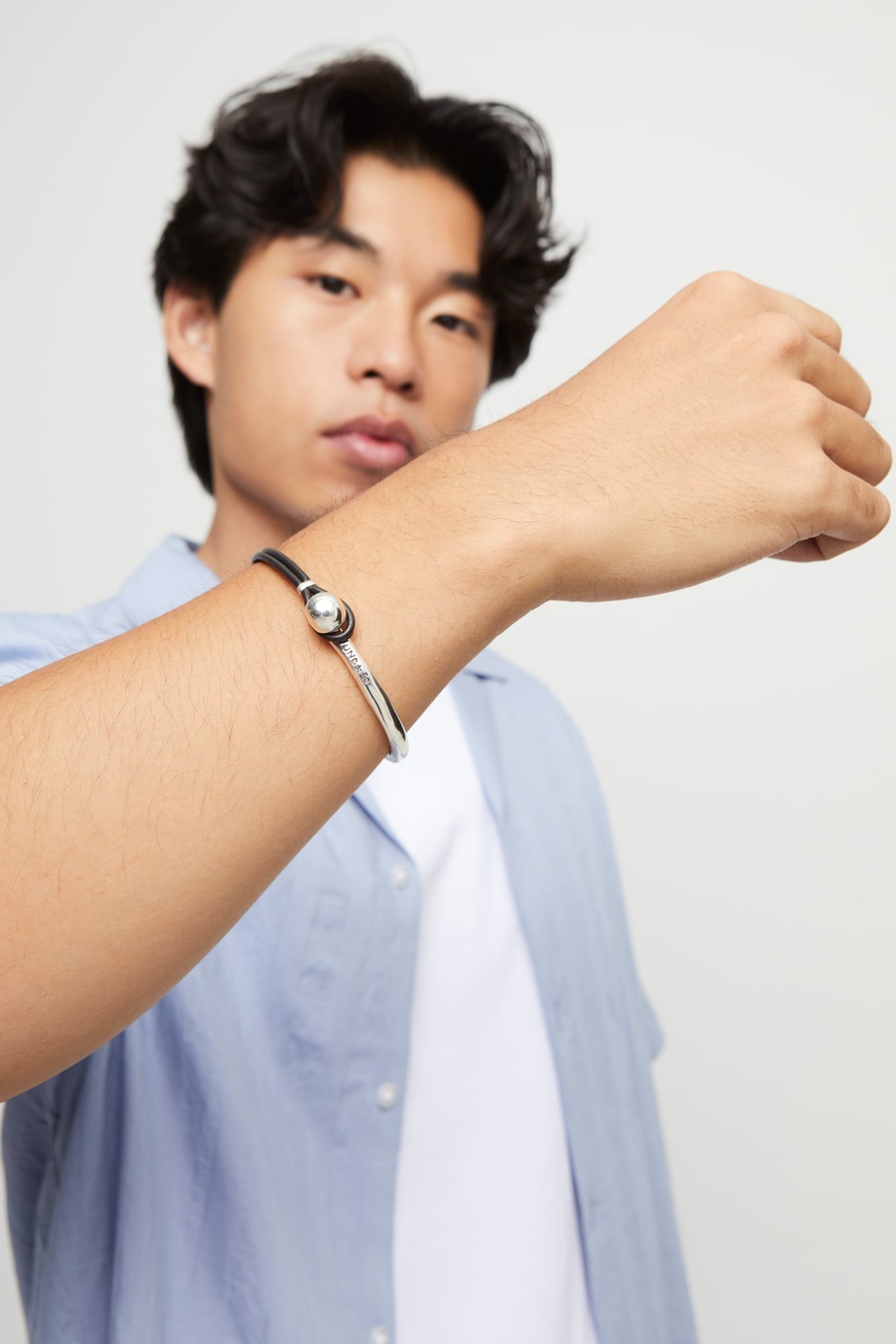 SER Intrepida bracelet on wrist: silver cuff with dark leather strap and round bead