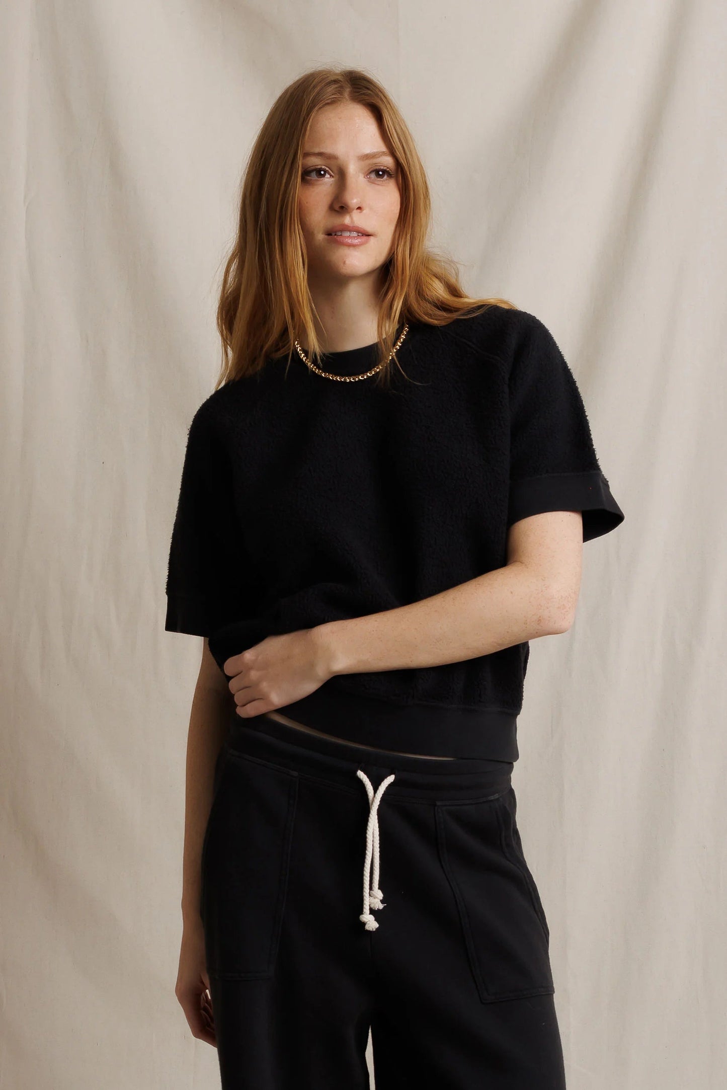 Black fleece short-sleeve sweatshirt with matching drawstring pants and side seam pocket