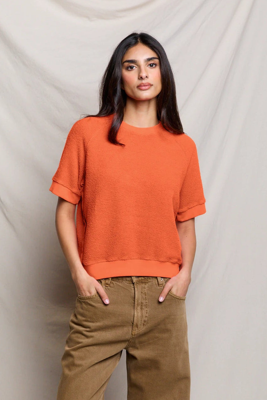 Orange fleece short-sleeve sweatshirt with crew neck, styled with olive pants