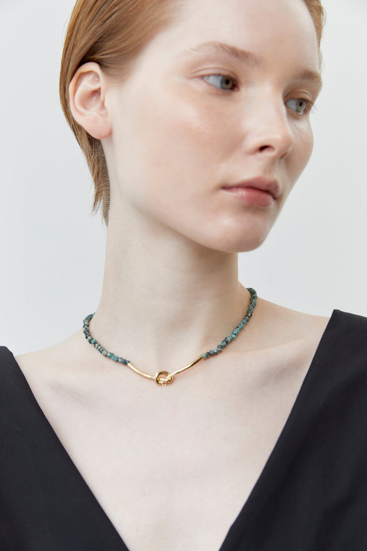 Beaded necklace with dark green and gray beads and gold clasp, worn at neck