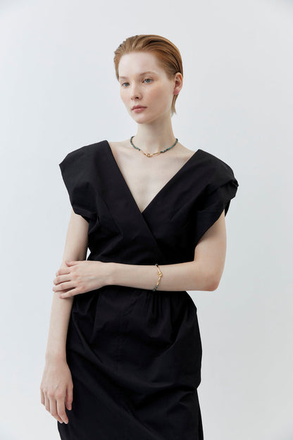 Beaded necklace with dark green and gray beads and gold clasp, worn on collarbone