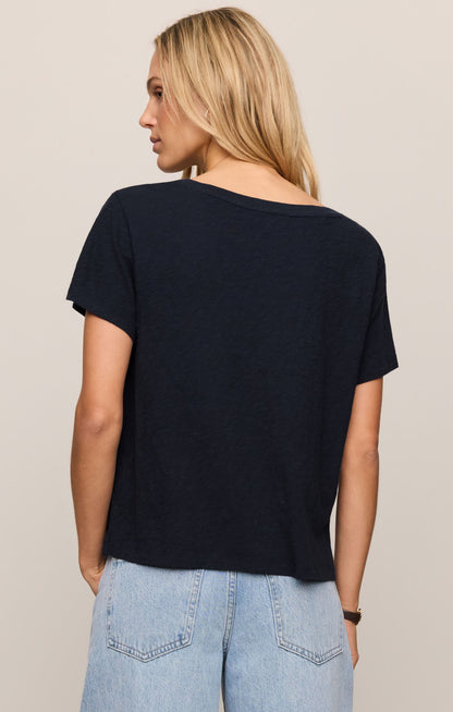 Woman wearing a black t-shirt and light blue jeans on a beige background