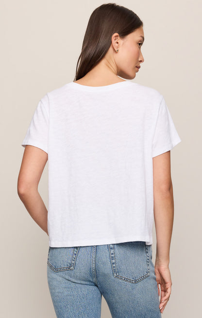 Woman wearing a white t-shirt and blue jeans against a beige background