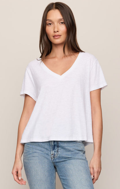Woman wearing a white t-shirt and blue jeans against a beige background