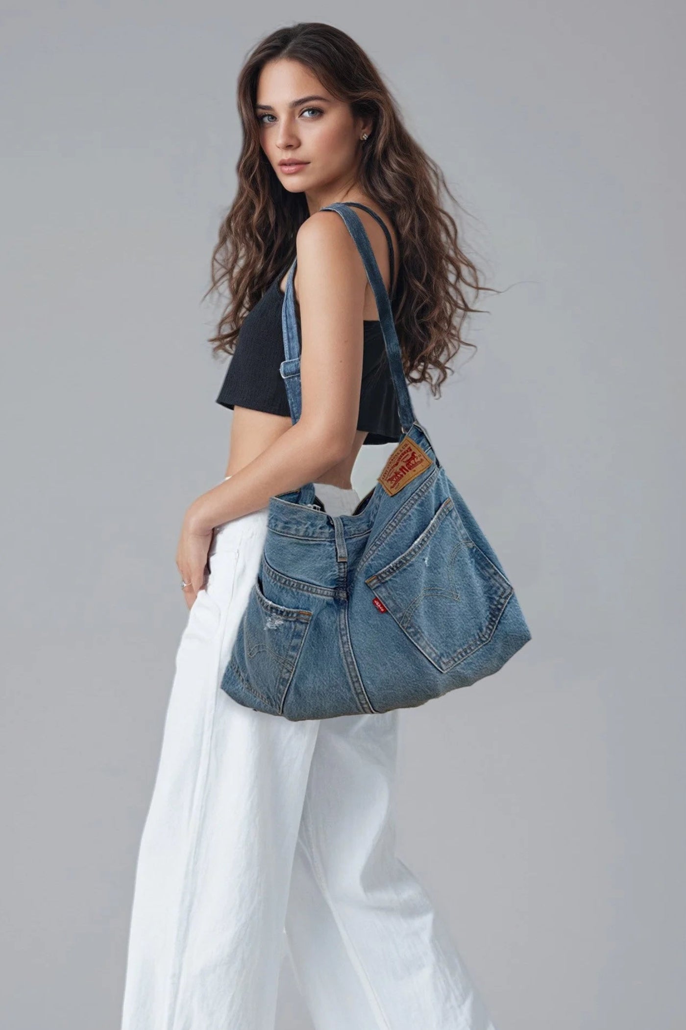 Woman holding a denim handbag against a gray background