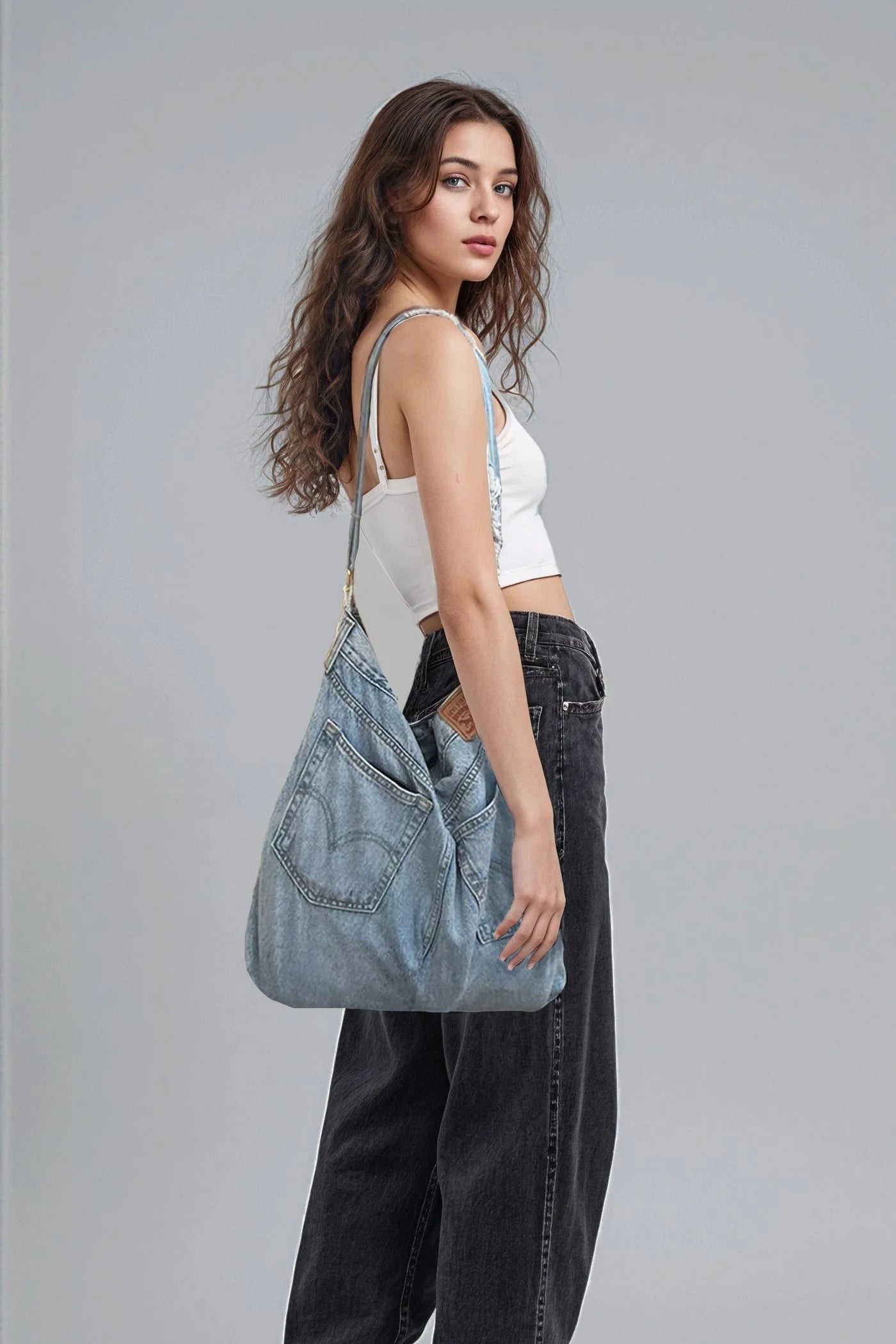 Woman holding a denim bag against a gray background
