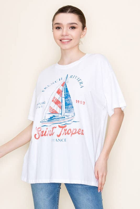 Woman wearing a white t-shirt with a sailboat graphic and text on a beige background