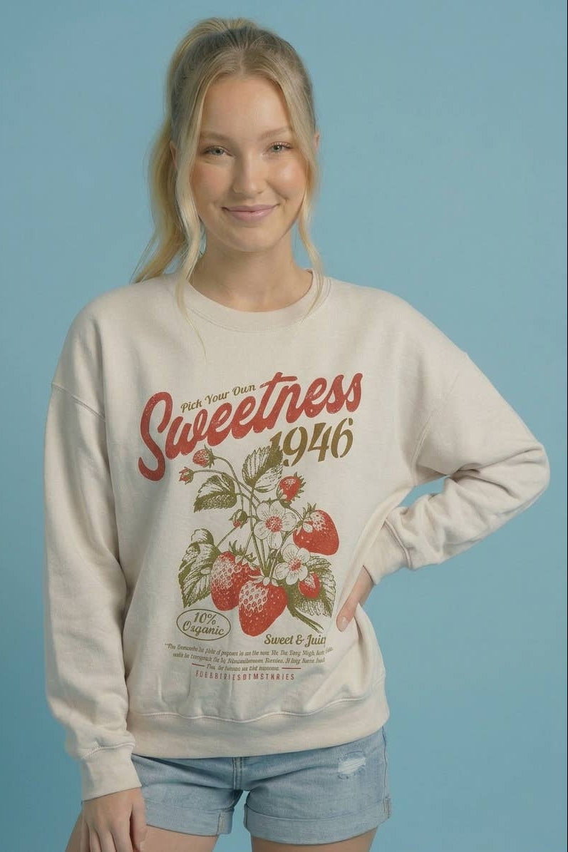 Ivory crewneck sweatshirt with 'Sweetness 1946' strawberry print, hand on hip