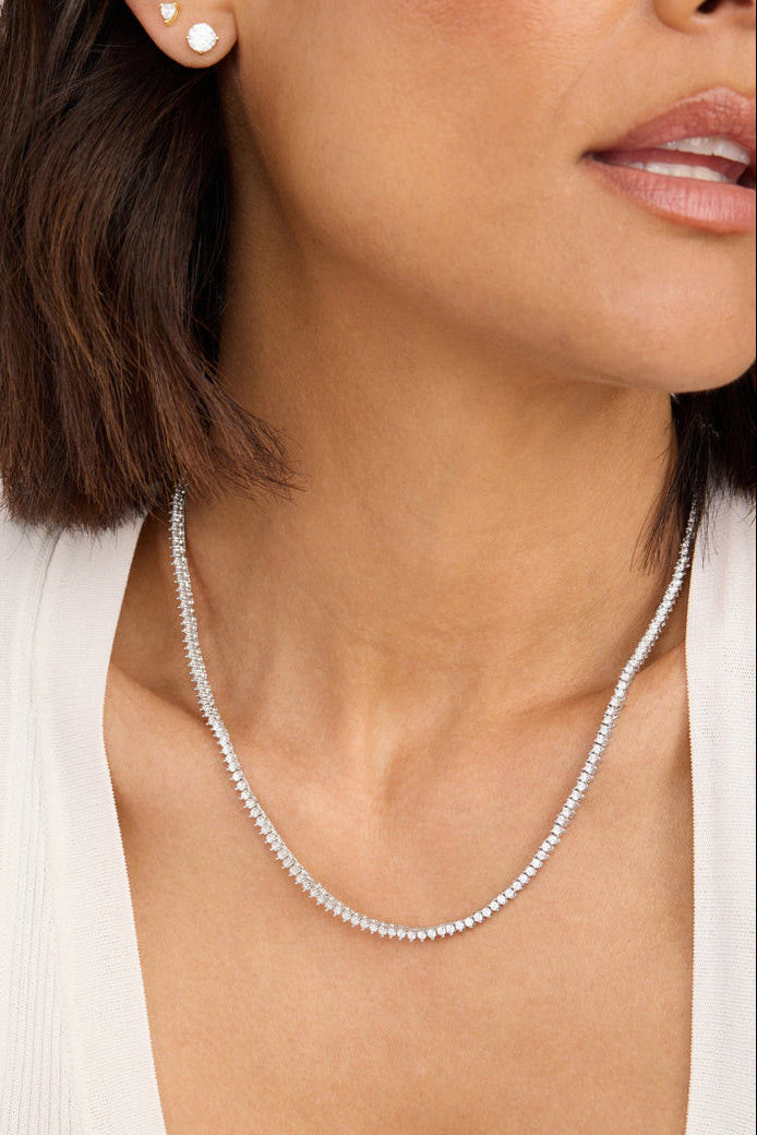 Silver tennis necklace with small white stones, close-up on neckline