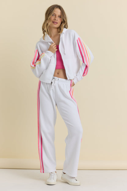 Woman wearing a white tracksuit with pink stripes on a beige background