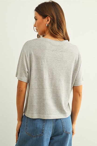 Back view of woman wearing a grey & white striped shirt and blue jeans on a plain background