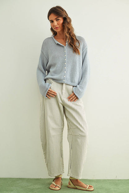 Woman wearing a sky blue shirt and striped pants against a white background