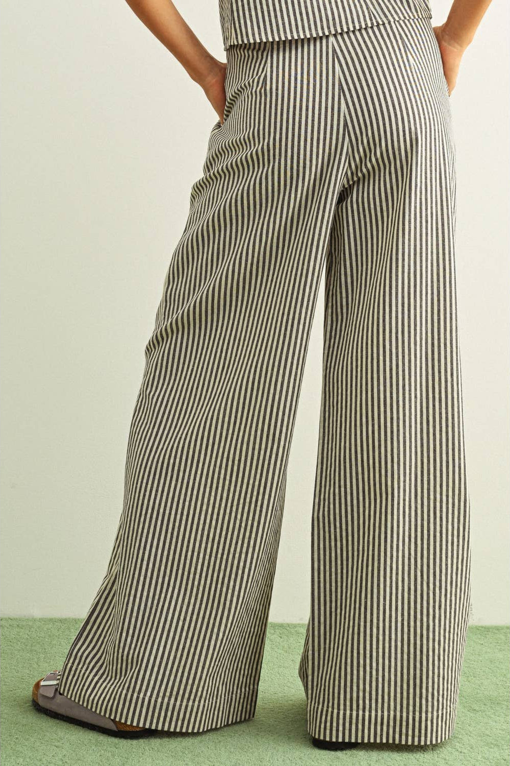 Black and white Striped wide-leg pants worn by a person on a light green background