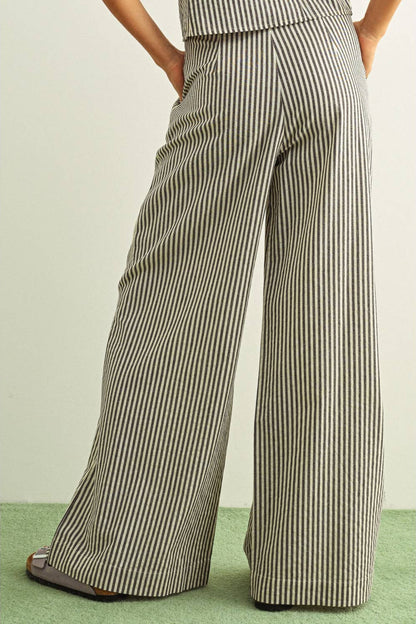 Black and white Striped wide-leg pants worn by a person on a light green background