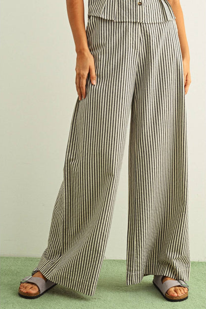 Front view of Person wearing black and white striped wide-leg pants on a plain background