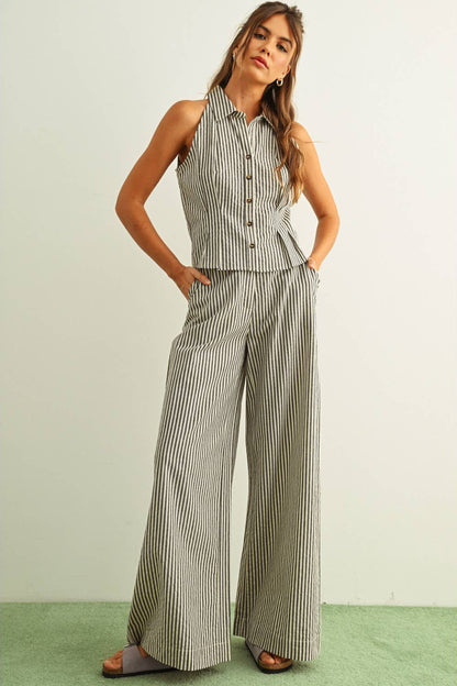 Woman wearing a striped sleeveless top and black striped wide-leg pants on a light green background