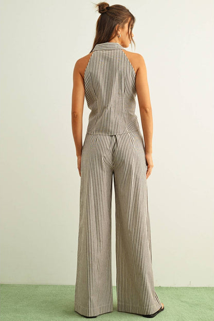A woman viewed from behind wearing a sleeveless halter-style matching set with wide leg pants and vertical pinstripes in brown and white, standing against a plain light wall with a green floor.