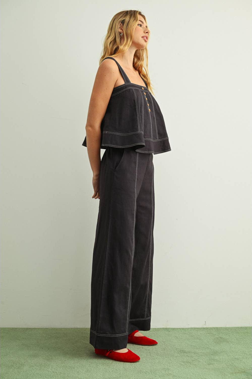 Side view of woman wearing navy wide leg linen pants with a matching navy linen sleeveless top