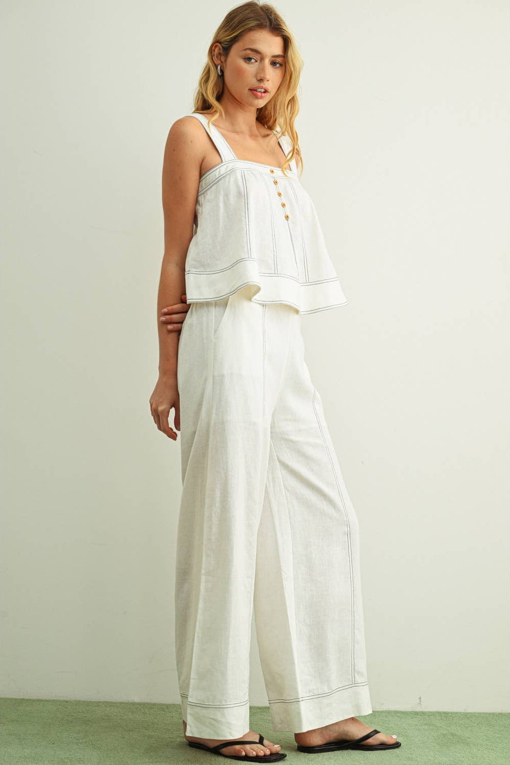 Front view of woman wearing white wide leg linen pants with a matching white linen stitched sleeveless top