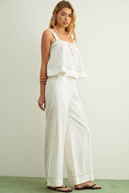 Front view of woman wearing white wide leg linen pants with a matching white linen stitched sleeveless top