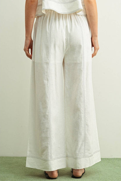 back view of woman wearing white stitched wide leg linen pants 