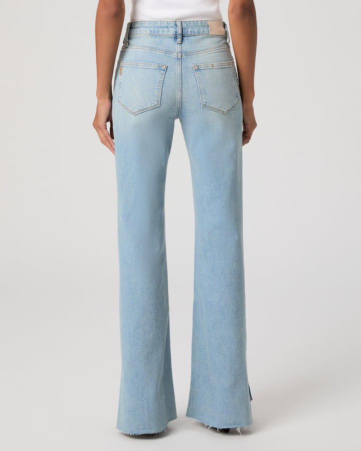 A model shown from the back wearing light-wash montebello blue sofia flare jeans, photographed against a clean light gray studio background.