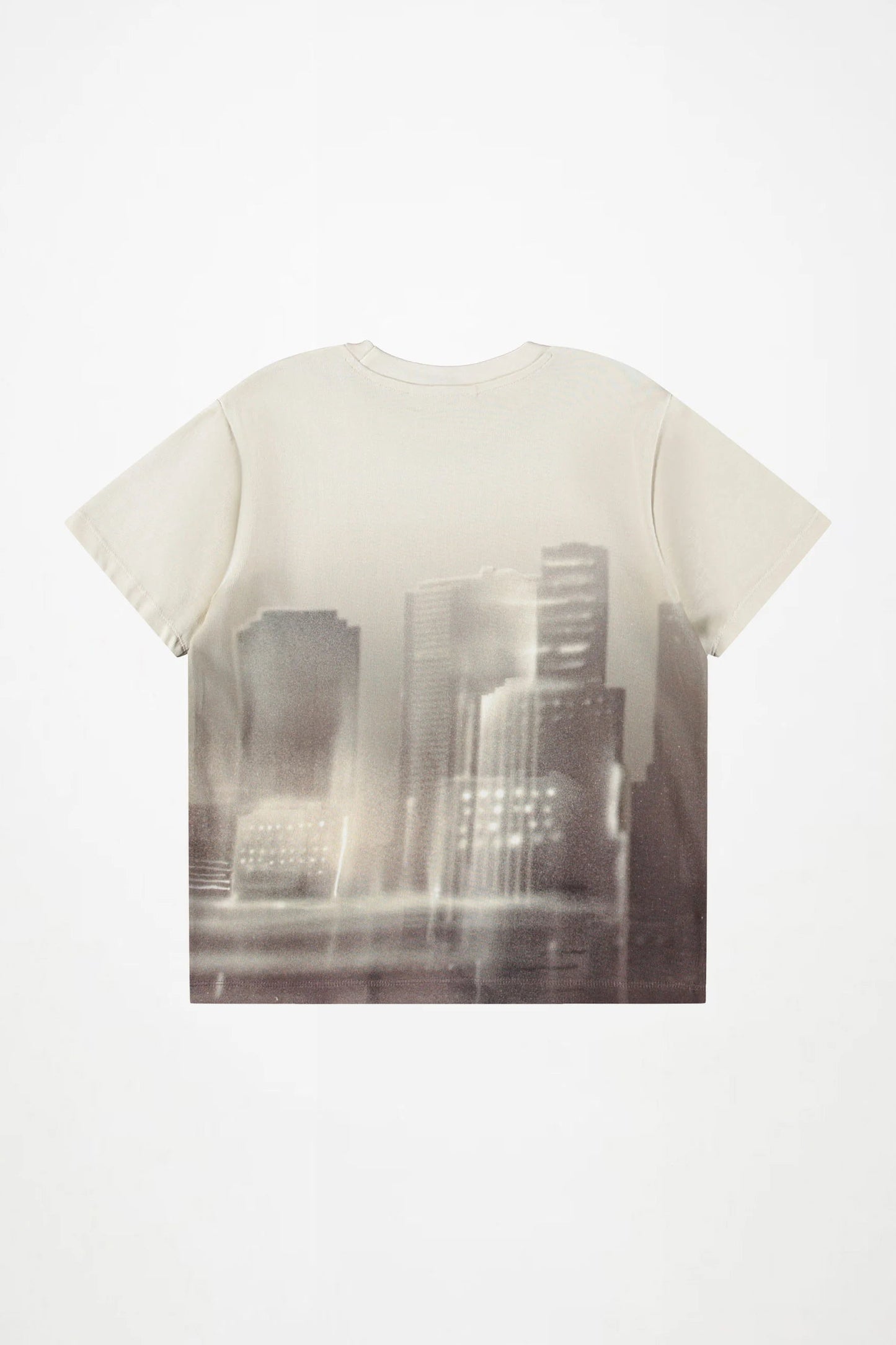 A cream-colored short-sleeve t-shirt featuring a large, tonal photographic print of a city skyline on the front, displayed against a clean white background.