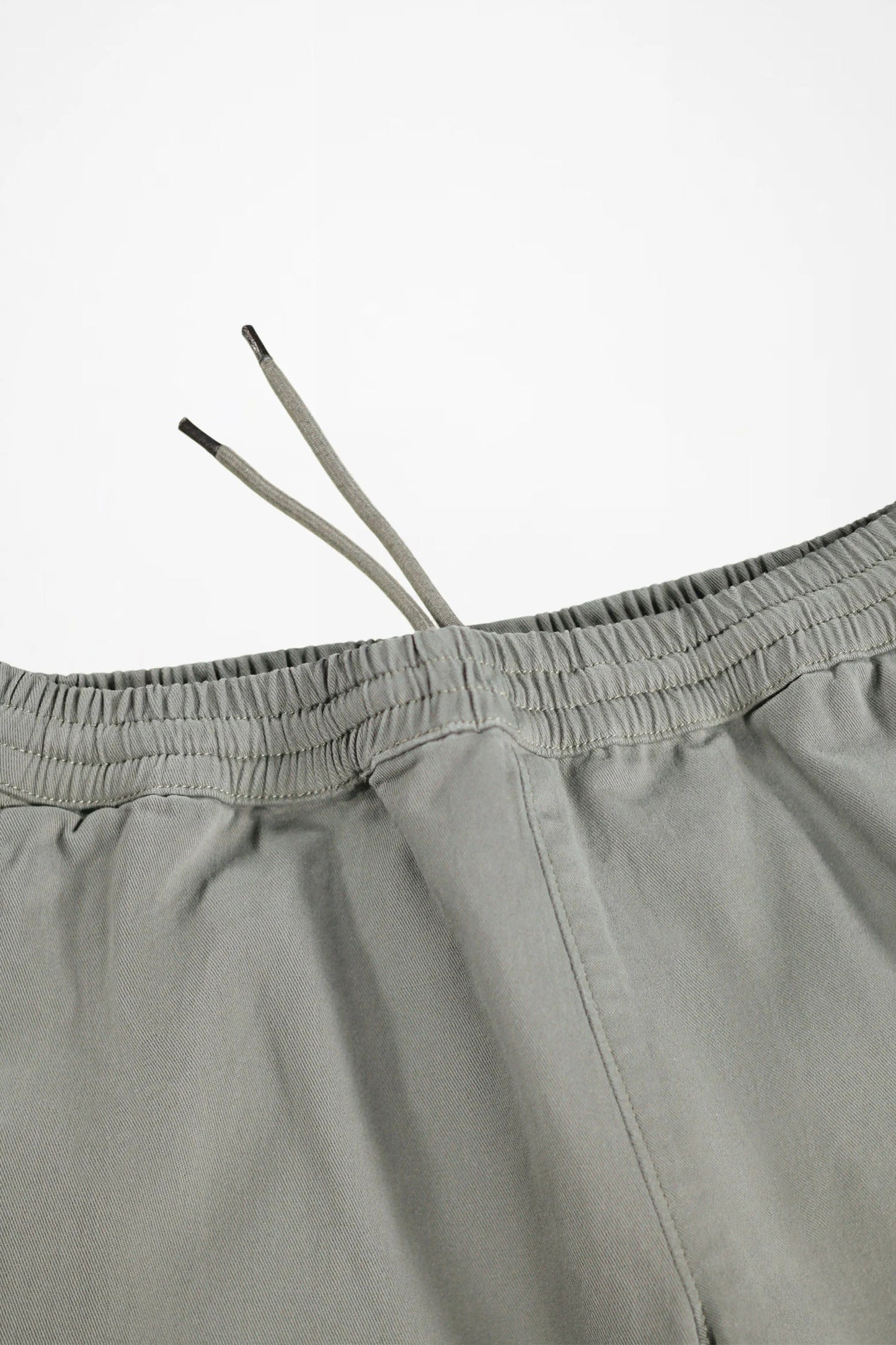 Close-up of a pair of light gray drawstring shorts showing the elastic waistband and drawstrings against a plain white background.