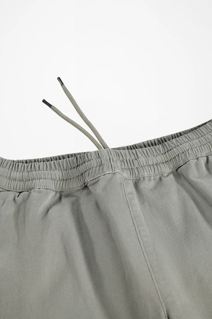Close-up of a pair of light gray drawstring shorts showing the elastic waistband and drawstrings against a plain white background.