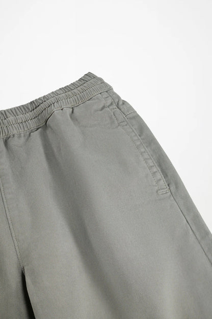 Close-up of a pair of light gray trousers showing the elastic waistband and side pocket detail against a plain white background.