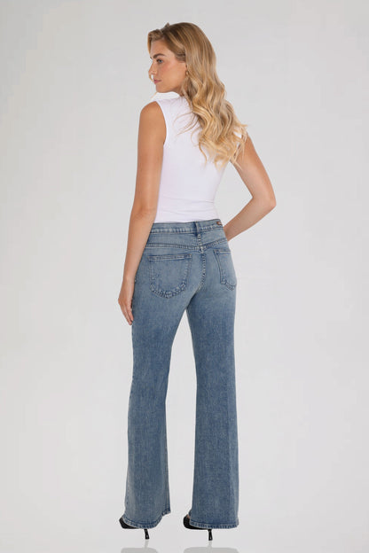A woman is shown from the back wearing  a white sleeveless top and bleu perle grace mid rise jeans standing against a plain background