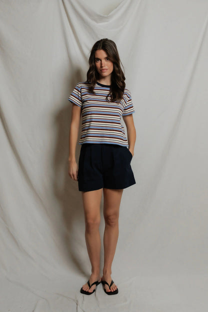 Woman wearing a Dawn Jersey Ringer striped shirt in Navy Pacific Stripe and black shorts against a plain background