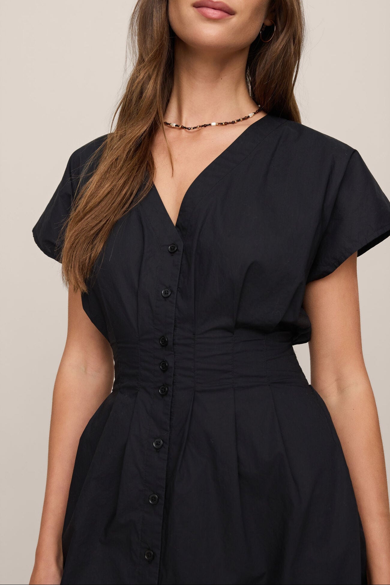 Woman wearing the black Sanna Mini dress with a plain background