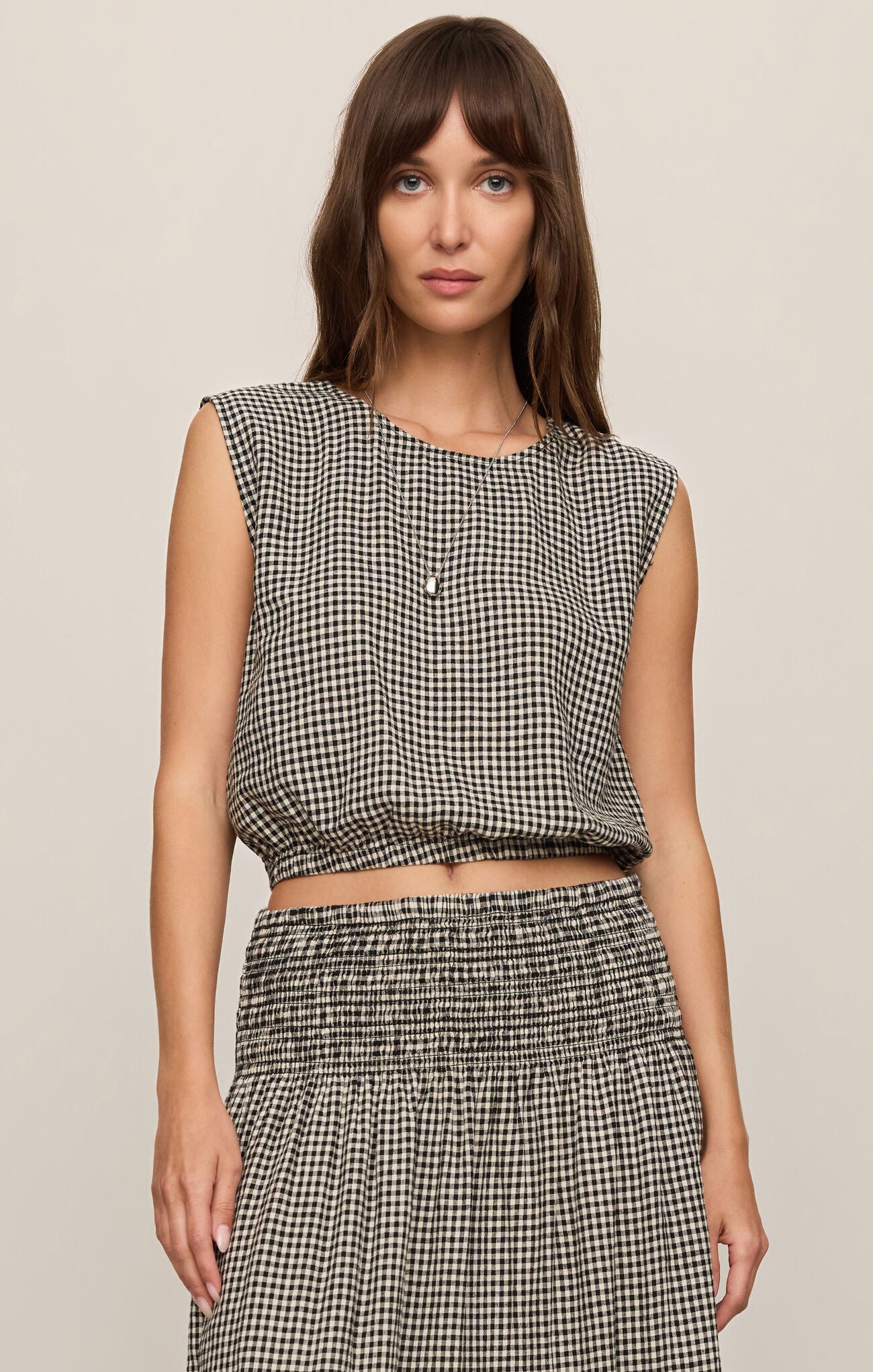 Front view of woman wearing Merit Gingham top in black & white with matching skirt 