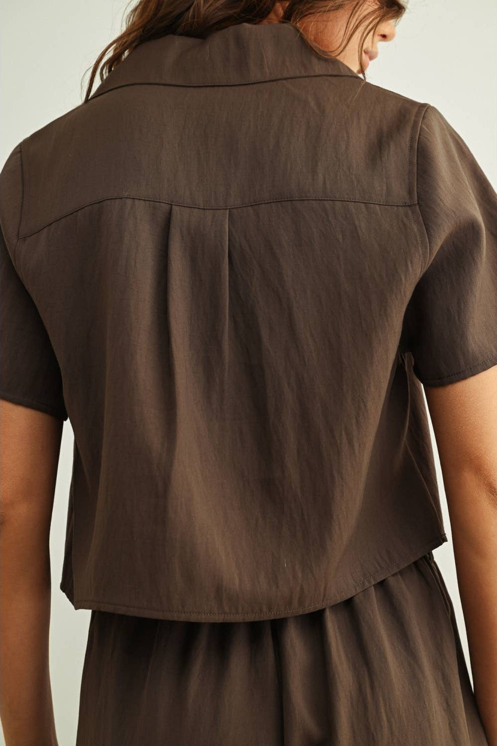 Brown short-sleeve shirt worn by a person on a light green background