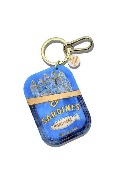 A blue Sardines keychain charm designed to look like a Sardines tin, featuring a gold clasp and a small branded tag, shown on a plain white background.