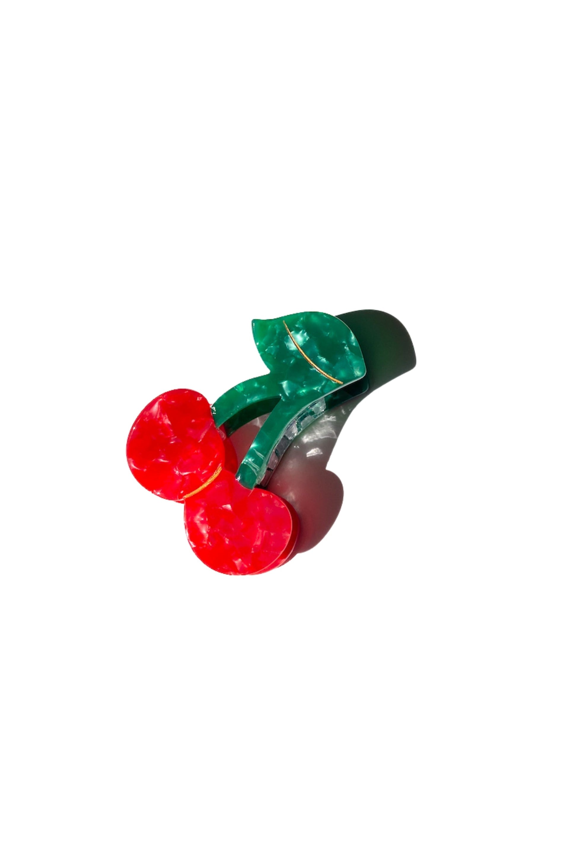 Decorative hair clip with red cherries and green leaves on a white background