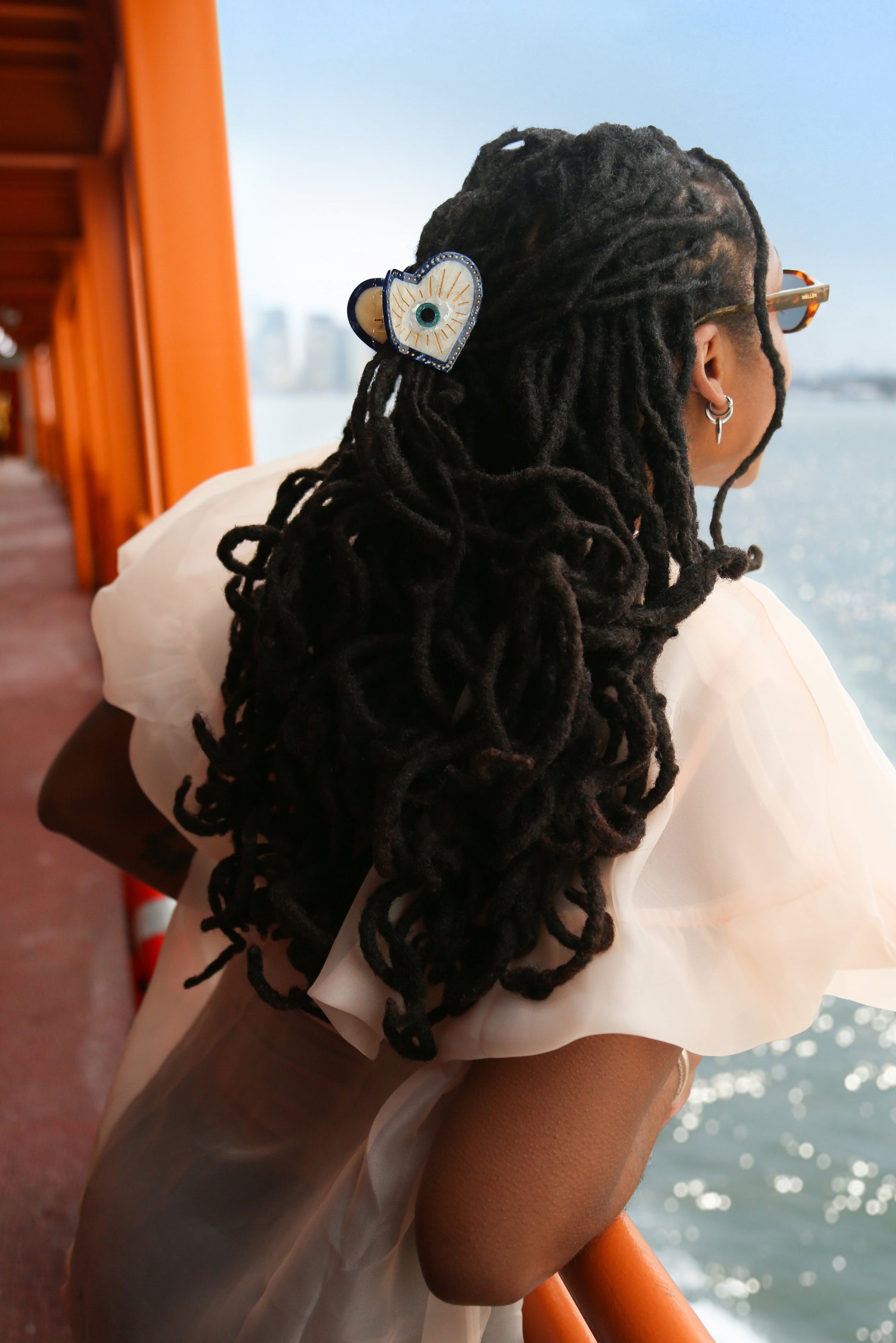 Person with styled hair with a blue lucky eye hair clip by a waterfront