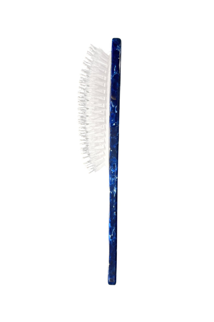 Blue-handled hairbrush with white bristles on a white background
