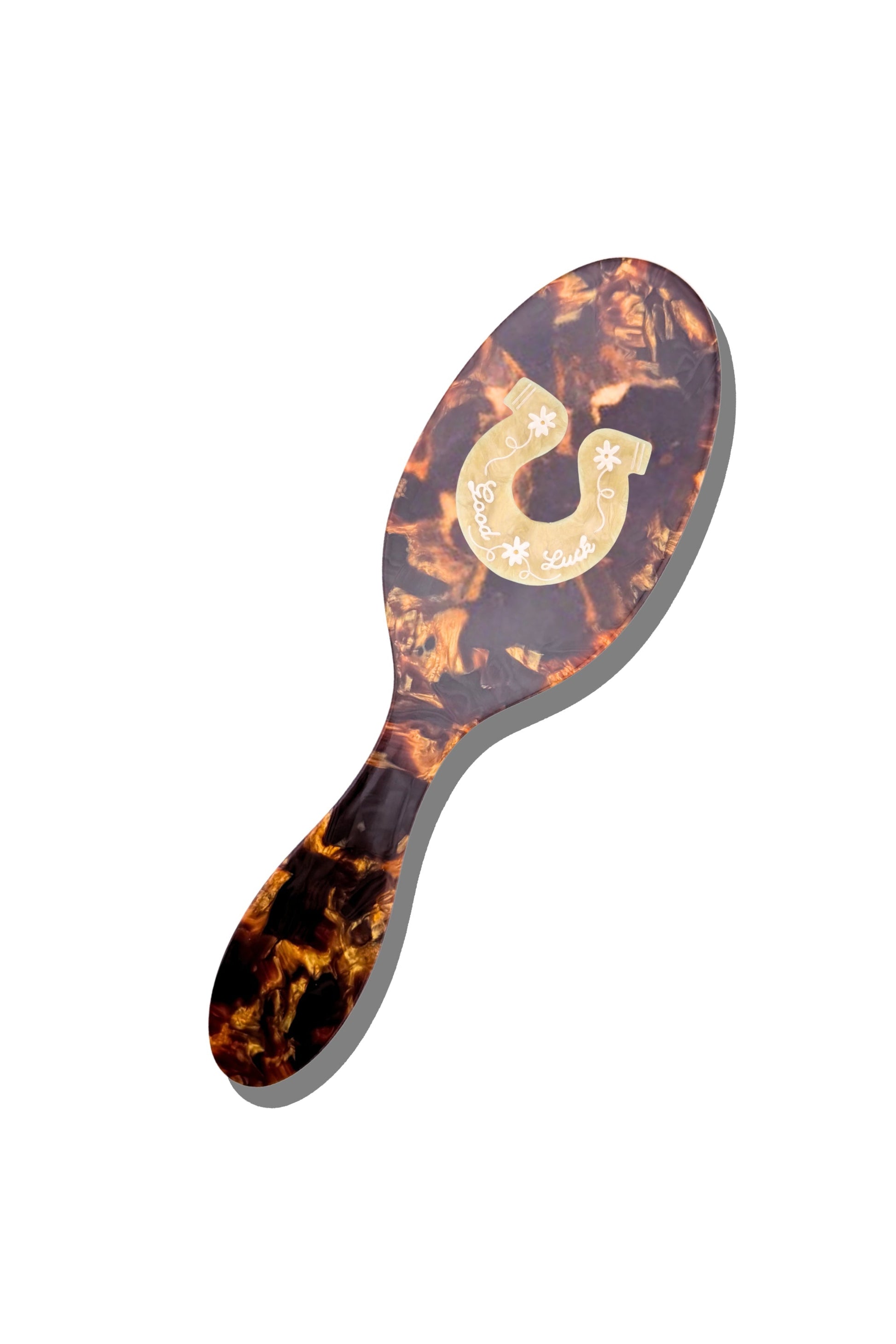 Tortoiseshell-patterned hairbrush with a gold horseshoe logo on a white background