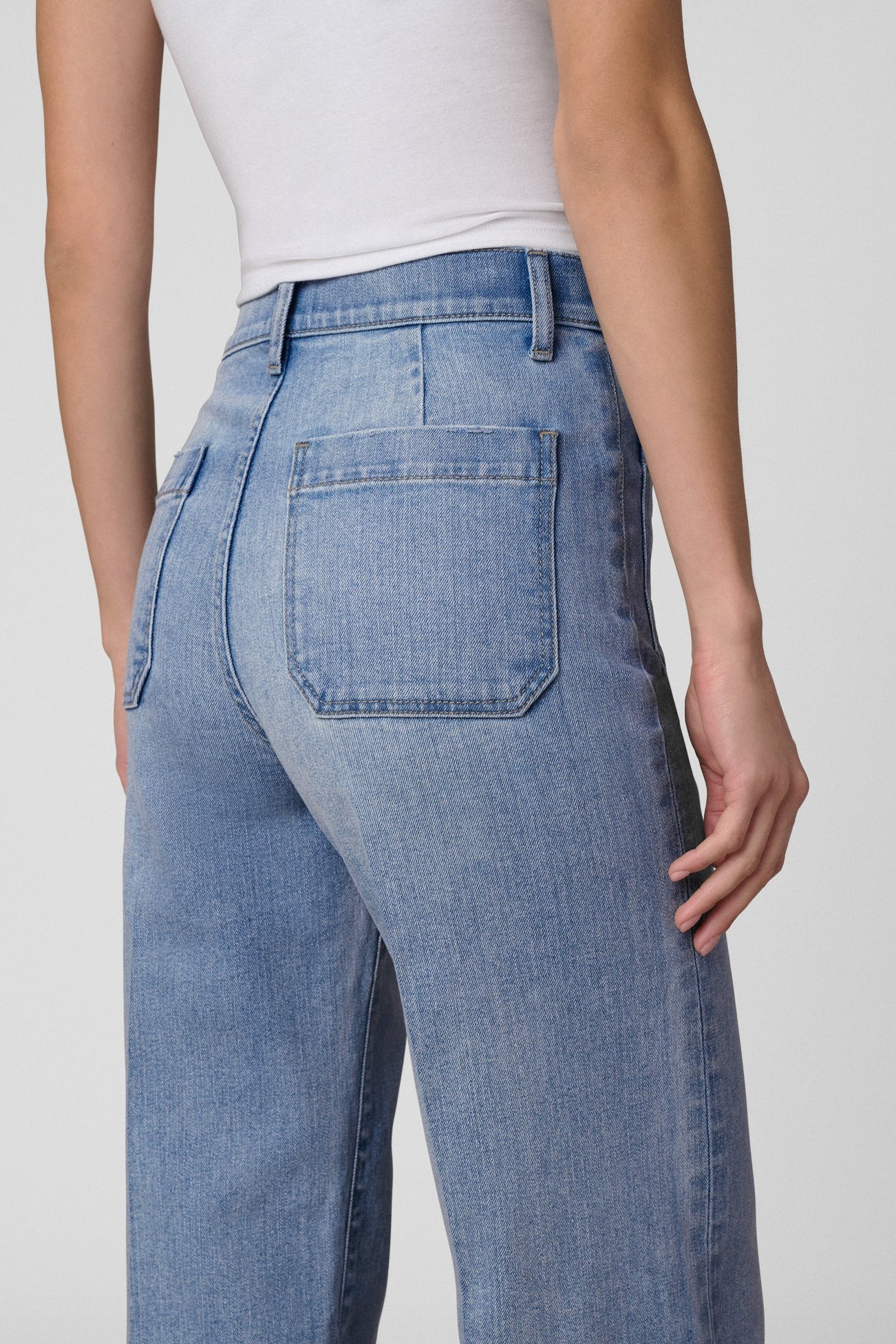 Close up back pocket view of a Woman wearing a white t-shirt and Joe's Mia Patch Pocket blue jeans in Amiable color on a white background